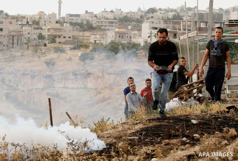 A Palestinian covers a tear gas canister fired by Israeli policemen as they try to make their way to attend the second Friday prayer of the holy fasting month of Ramadan in Jerusalem's Al-Aqsa mosque, after Israeli polic...