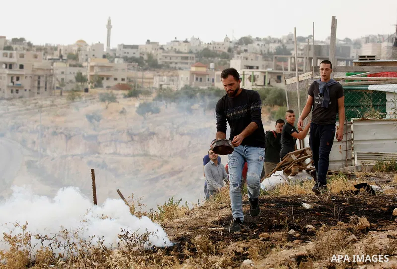 A Palestinian covers a tear gas canister fired by Israeli policemen as they try to make their way to attend the second Friday prayer of the holy fasting month of Ramadan in Jerusalem's Al-Aqsa mosque, after Israeli polic...