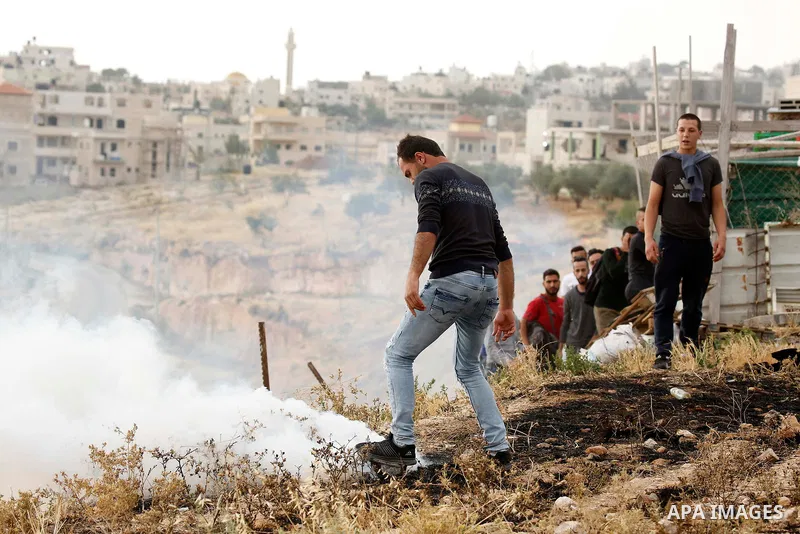 A Palestinian covers a tear gas canister fired by Israeli policemen as they try to make their way to attend the second Friday prayer of the holy fasting month of Ramadan in Jerusalem's Al-Aqsa mosque, after Israeli polic...