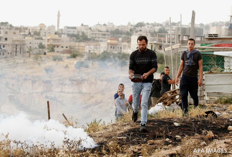 A Palestinian covers a tear gas canister fired by Israeli policemen as they try to make their way to attend the second Friday prayer of the holy fasting month of Ramadan in Jerusalem's Al-Aqsa mosque, after Israeli polic...