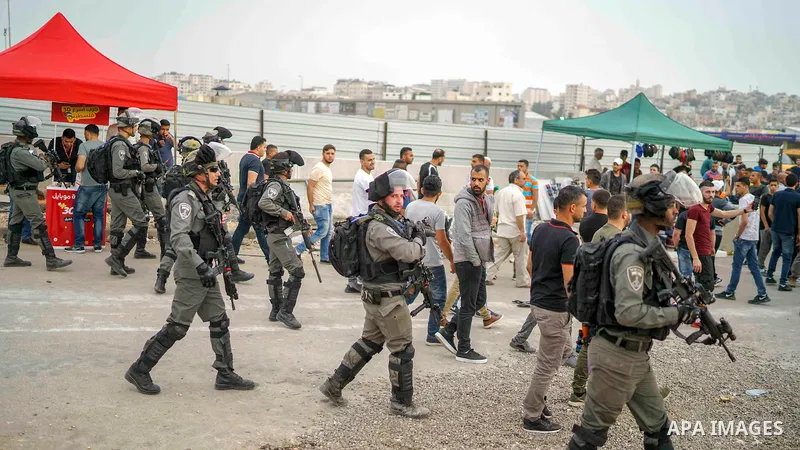 Israeli security forces stand guard as Palestinians make their way through Qalandia checkpoint to attend the second Friday prayer of the holy fasting month of Ramadan in Jerusalem's Al-Aqsa mosque, near Ramallah in the o...