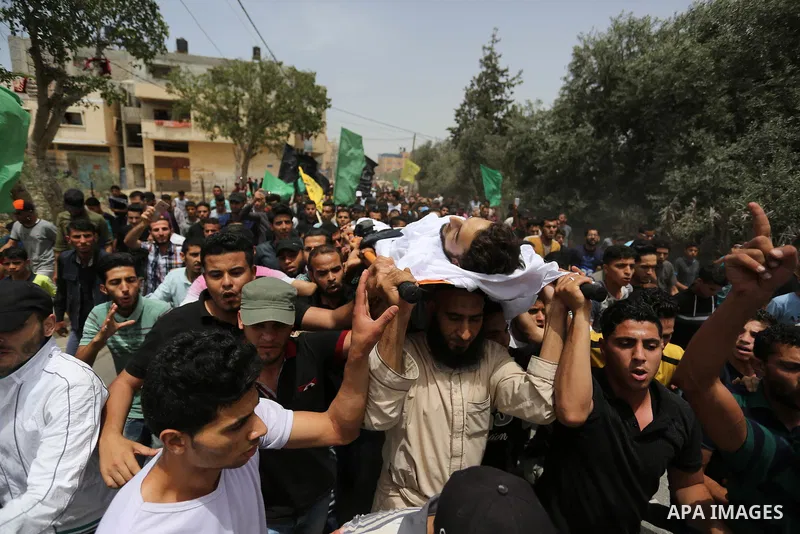 Palestinian mourners carry the body of Ahmed Qutoosh, 23, who died of his wounds endured during clashes with Israeli troops in a tent city protest where Palestinians demand the right to return to their homeland at the Is...