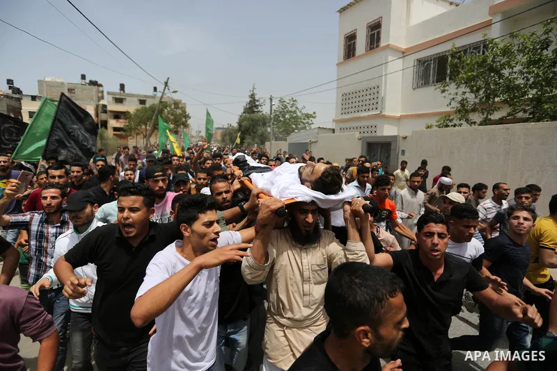 Palestinian mourners carry the body of Ahmed Qutoosh, 23, who died of his wounds endured during clashes with Israeli troops in a tent city protest where Palestinians demand the right to return to their homeland at the Is...