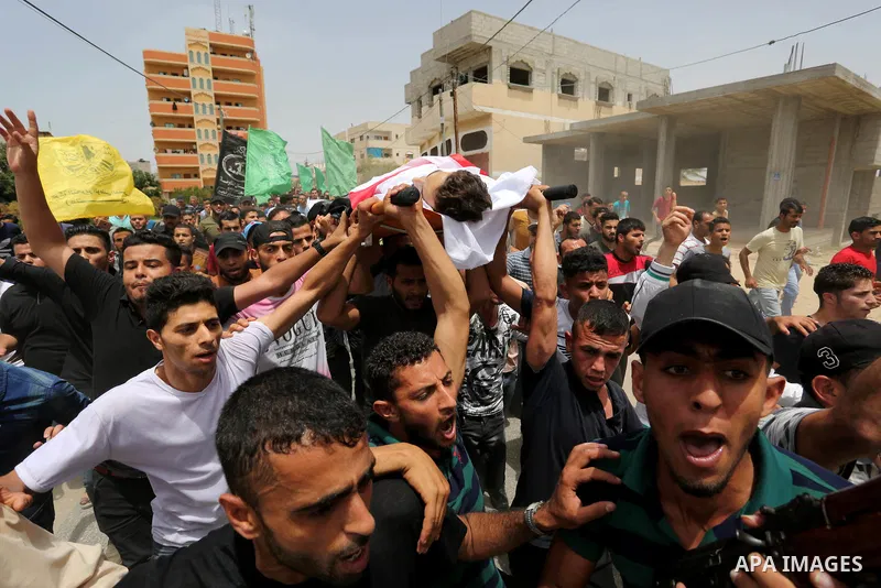 Palestinian mourners carry the body of Ahmed Qutoosh, 23, who died of his wounds endured during clashes with Israeli troops in a tent city protest where Palestinians demand the right to return to their homeland at the Is...