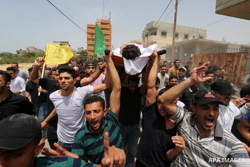 Palestinian mourners carry the body of Ahmed Qutoosh, 23, who died of his wounds endured during clashes with Israeli troops in a tent city protest where Palestinians demand the right to return to their homeland at the Is...
