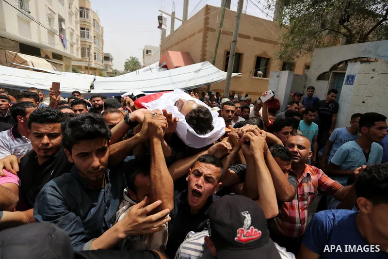 Palestinian mourners carry the body of Ahmed Qutoosh, 23, who died of his wounds endured during clashes with Israeli troops in a tent city protest where Palestinians demand the right to return to their homeland at the Is...