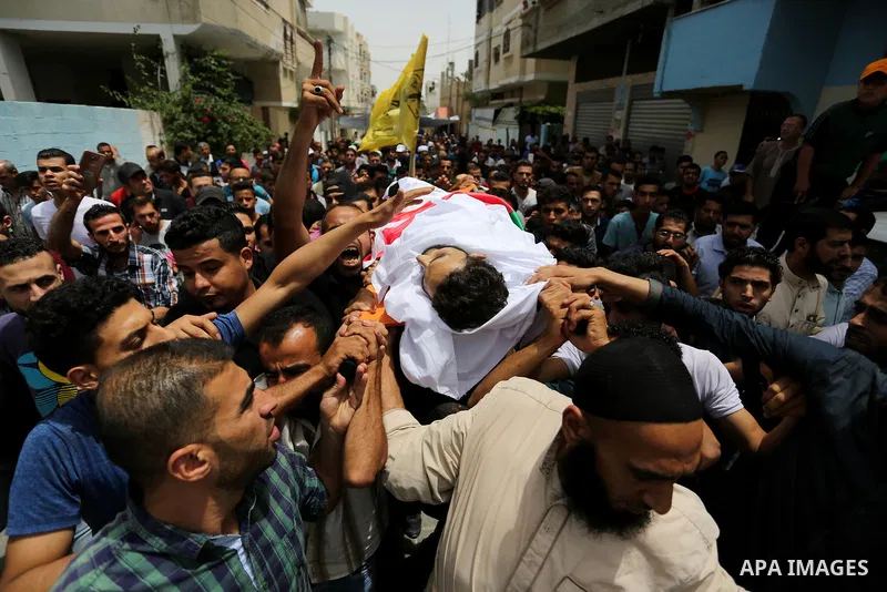 Palestinian mourners carry the body of Ahmed Qutoosh, 23, who died of his wounds endured during clashes with Israeli troops in a tent city protest where Palestinians demand the right to return to their homeland at the Is...