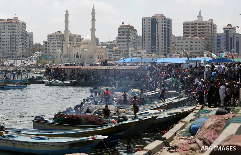 Palestinians watch ride fishing boats carrying Palestinian activists who are protesting and perhaps trying to breach Israel's naval blockade on Gaza, setting to sail from Gaza City harbour towards Europe on May 29, 2018....