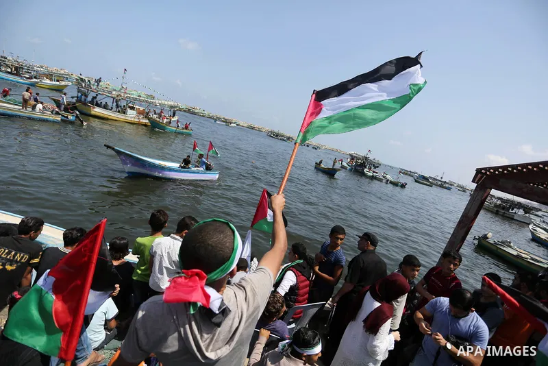 Palestinians watch ride fishing boats carrying Palestinian activists who are protesting and perhaps trying to breach Israel's naval blockade on Gaza, setting to sail from Gaza City harbour towards Europe on May 29, 2018....