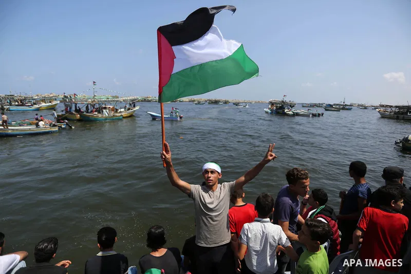 Palestinians watch ride fishing boats carrying Palestinian activists who are protesting and perhaps trying to breach Israel's naval blockade on Gaza, setting to sail from Gaza City harbour towards Europe on May 29, 2018....
