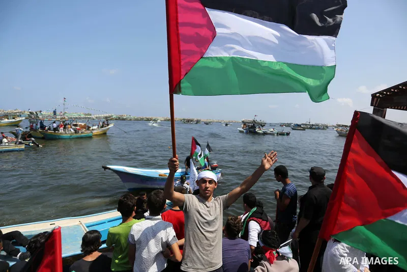 Palestinians watch ride fishing boats carrying Palestinian activists who are protesting and perhaps trying to breach Israel's naval blockade on Gaza, setting to sail from Gaza City harbour towards Europe on May 29, 2018....