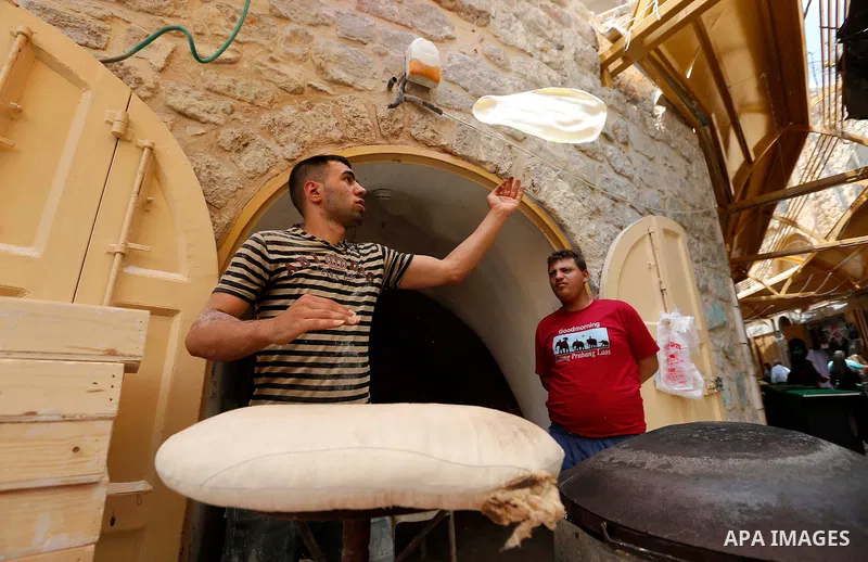 A Palestinian vendor sells bread at a market during the holy fasting month of Ramadan in the West Bank city of Hebron, May 30, 2018. Ramadan is sacred to Muslims because it is during that month that tradition says the Ko...