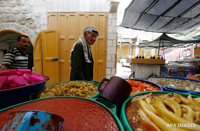 A Palestinian vendor sells pickles at a market during the holy fasting month of Ramadan in the West Bank city of Hebron, May 30, 2018. Ramadan is sacred to Muslims because it is during that month that tradition says the...