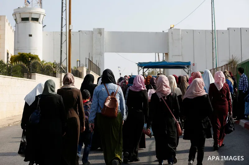 Palestinians make their way through an Israeli checkpoint along Israel's controversial separation barrier to attend the third Friday prayer of the holy fasting month of Ramadan in Jerusalem's Al-Aqsa mosque, in Bethlehem...