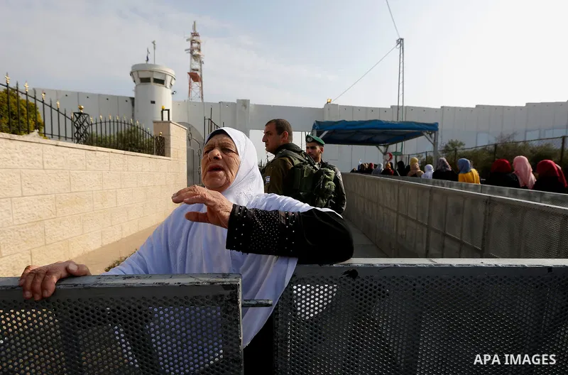 Palestinians make their way through an Israeli checkpoint along Israel's controversial separation barrier to attend the third Friday prayer of the holy fasting month of Ramadan in Jerusalem's Al-Aqsa mosque, in Bethlehem...