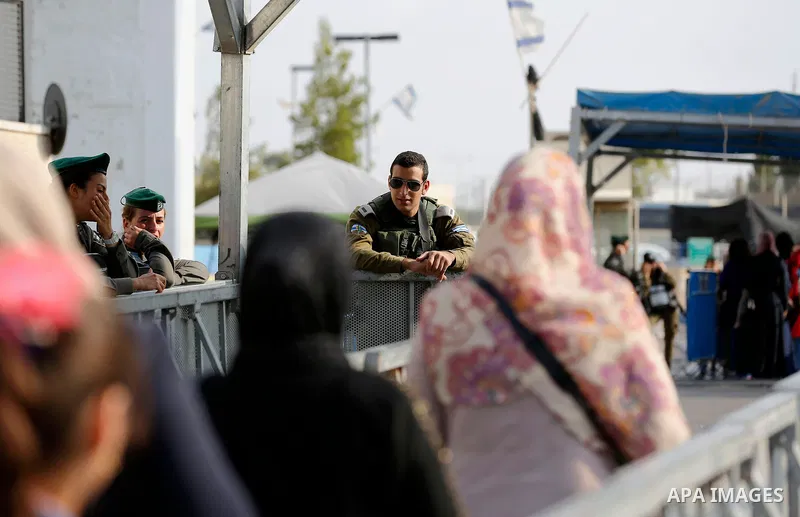Palestinians make their way through an Israeli checkpoint along Israel's controversial separation barrier to attend the third Friday prayer of the holy fasting month of Ramadan in Jerusalem's Al-Aqsa mosque, in Bethlehem...