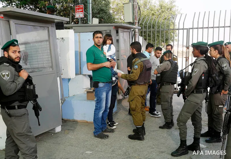 Palestinians make their way through an Israeli checkpoint along Israel's controversial separation barrier to attend the third Friday prayer of the holy fasting month of Ramadan in Jerusalem's Al-Aqsa mosque, in Bethlehem...