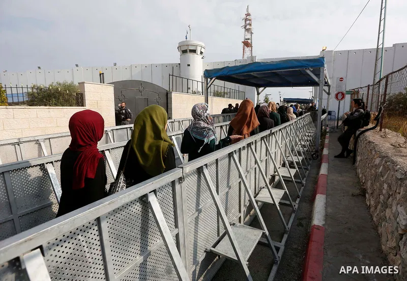 Palestinians make their way through an Israeli checkpoint along Israel's controversial separation barrier to attend the third Friday prayer of the holy fasting month of Ramadan in Jerusalem's Al-Aqsa mosque, in Bethlehem...