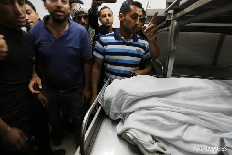 Colleagues of Palestinian medic Razan al-Najar, 21, who was killed during a protest at the Israel-Gaza border, mourn over her body at a hospital morgue in Khan Younis in the southern Gaza Strip, on June 1, 2018. Photo by...