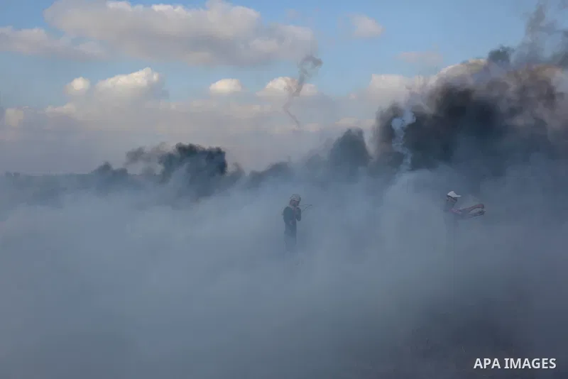 Palestinian protesters run for cover from tear gas canisters fired by Israeli security forces during clashes in a tent city protest where Palestinians demand the right to return to their homeland and against U.S. embassy...