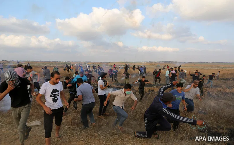 Palestinian protesters run for cover from tear gas canisters fired by Israeli security forces during clashes in a tent city protest where Palestinians demand the right to return to their homeland and against U.S. embassy...