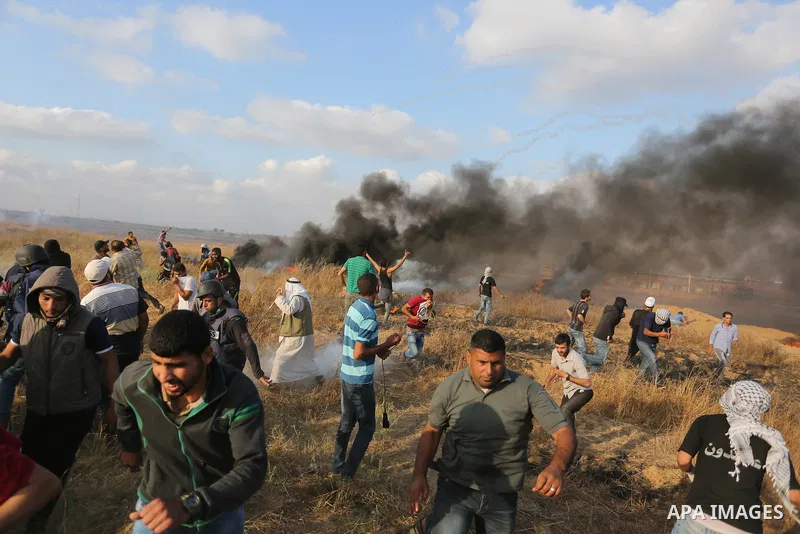 Palestinian protesters run for cover from tear gas canisters fired by Israeli security forces during clashes in a tent city protest where Palestinians demand the right to return to their homeland and against U.S. embassy...
