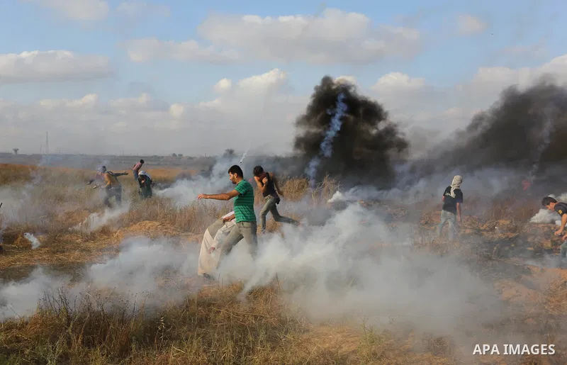 Palestinian protesters run for cover from tear gas canisters fired by Israeli security forces during clashes in a tent city protest where Palestinians demand the right to return to their homeland and against U.S. embassy...