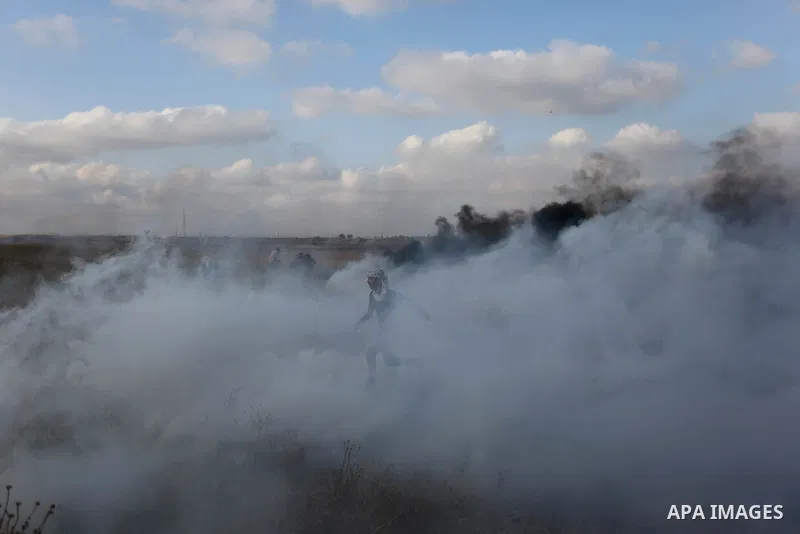 Palestinian protesters run for cover from tear gas canisters fired by Israeli security forces during clashes in a tent city protest where Palestinians demand the right to return to their homeland and against U.S. embassy...
