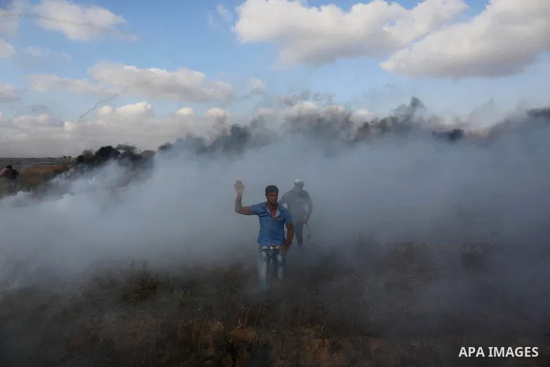 Palestinian protesters run for cover from tear gas canisters fired by Israeli security forces during clashes in a tent city protest where Palestinians demand the right to return to their homeland and against U.S. embassy...