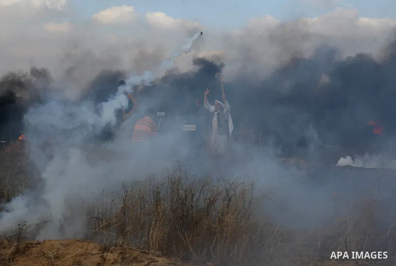 Palestinian protesters run for cover from tear gas canisters fired by Israeli security forces during clashes in a tent city protest where Palestinians demand the right to return to their homeland and against U.S. embassy...