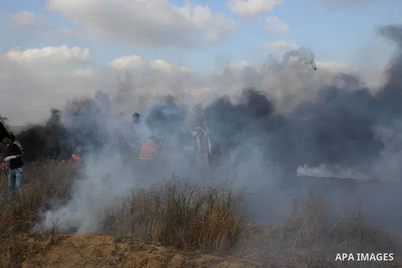 Palestinian protesters run for cover from tear gas canisters fired by Israeli security forces during clashes in a tent city protest where Palestinians demand the right to return to their homeland and against U.S. embassy...