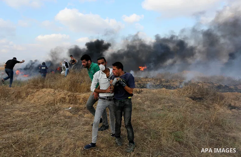 Palestinian protesters run for cover from tear gas canisters fired by Israeli security forces during clashes in a tent city protest where Palestinians demand the right to return to their homeland and against U.S. embassy...