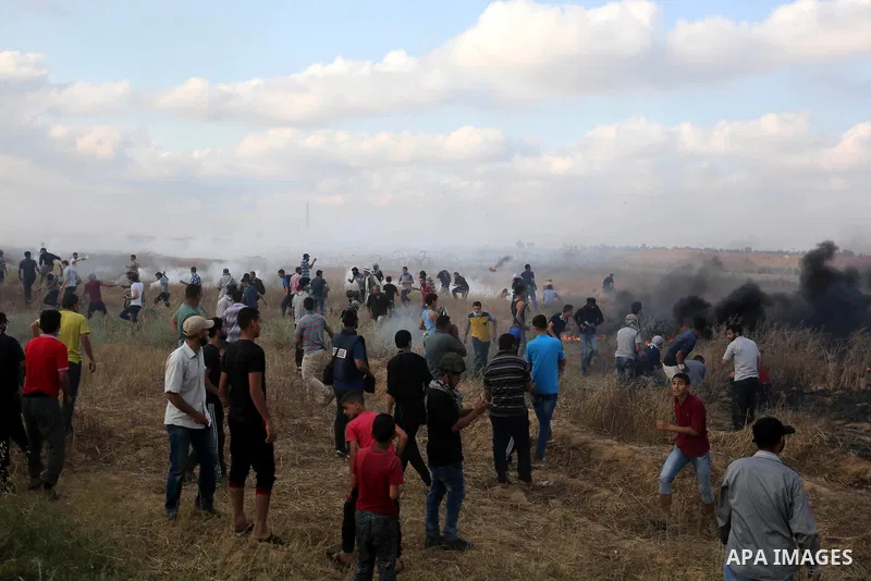 Palestinian protesters run for cover from tear gas canisters fired by Israeli security forces during clashes in a tent city protest where Palestinians demand the right to return to their homeland and against U.S. embassy...
