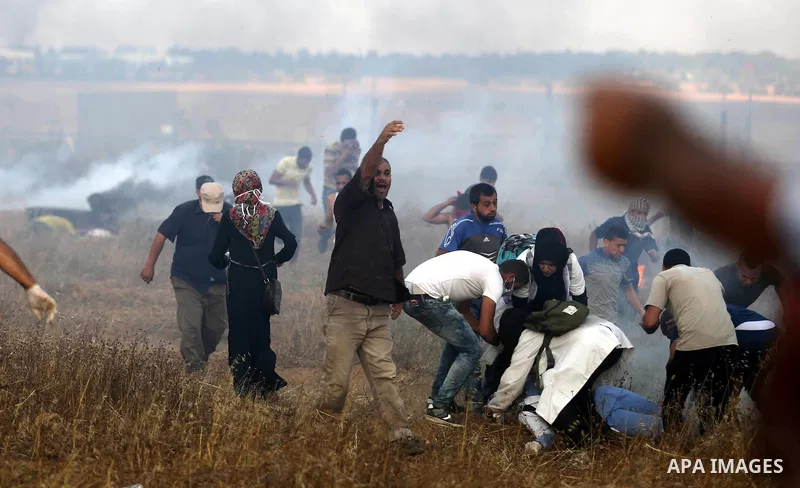 Palestinian protesters run for cover from tear gas canisters fired by Israeli security forces during clashes in a tent city protest where Palestinians demand the right to return to their homeland and against U.S. embassy...