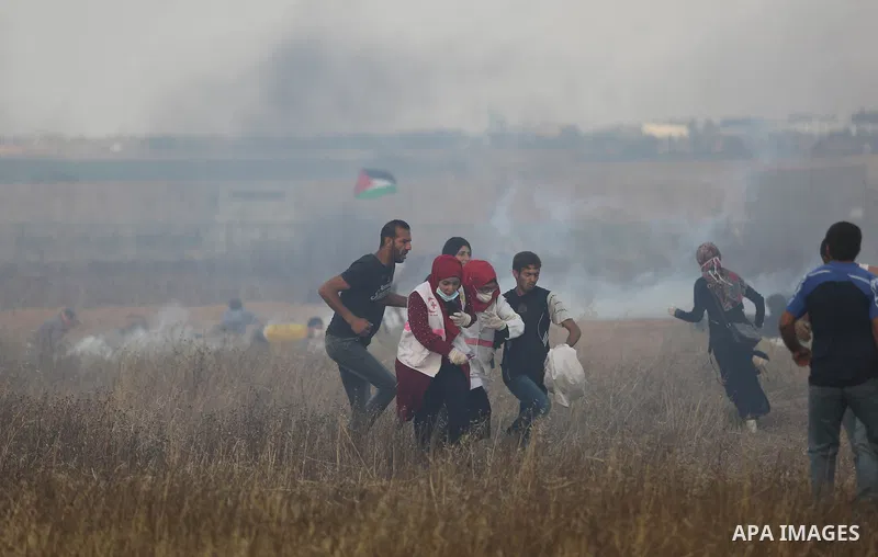Palestinian protesters run for cover from tear gas canisters fired by Israeli security forces during clashes in a tent city protest where Palestinians demand the right to return to their homeland and against U.S. embassy...