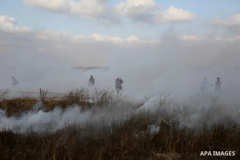 Palestinian protesters run for cover from tear gas canisters fired by Israeli security forces during clashes in a tent city protest where Palestinians demand the right to return to their homeland and against U.S. embassy...