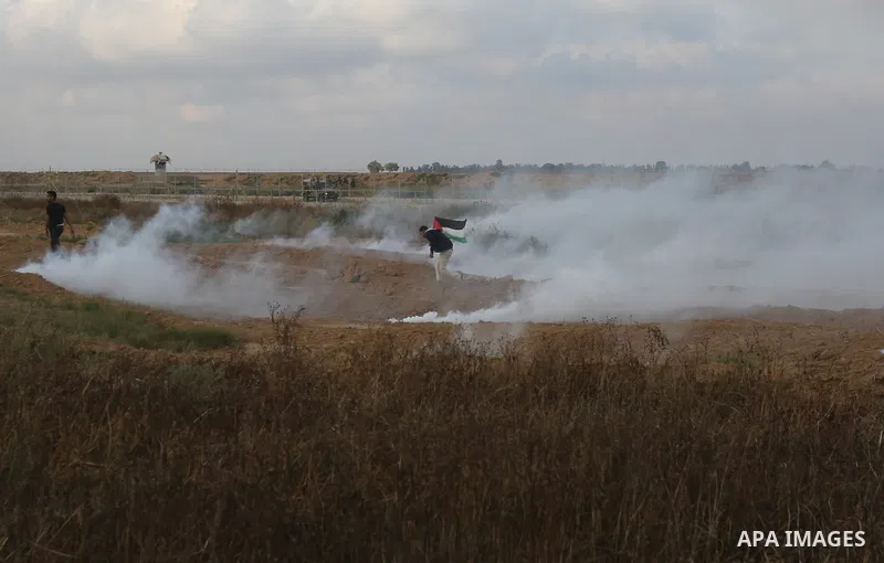Palestinian protesters run for cover from tear gas canisters fired by Israeli security forces during clashes in a tent city protest where Palestinians demand the right to return to their homeland and against U.S. embassy...