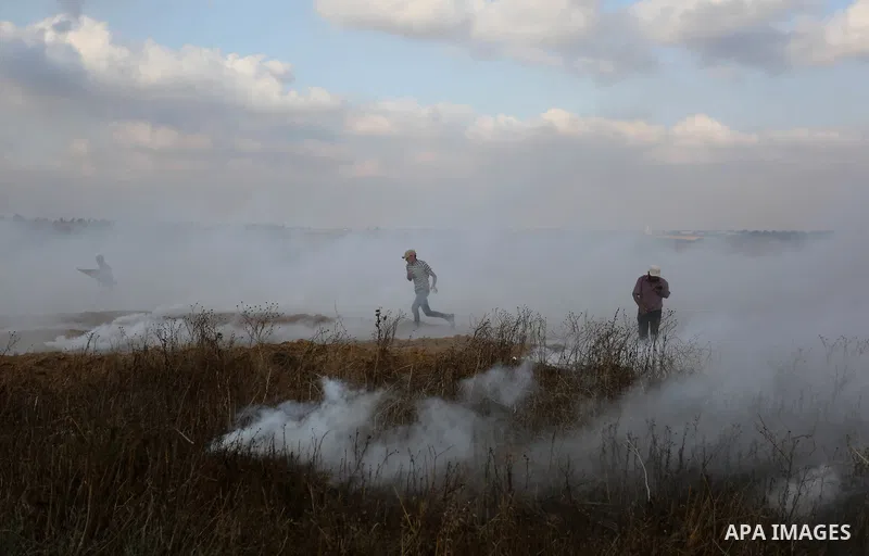 Palestinian protesters run for cover from tear gas canisters fired by Israeli security forces during clashes in a tent city protest where Palestinians demand the right to return to their homeland and against U.S. embassy...