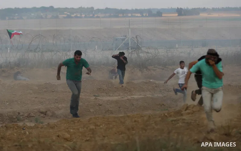 Palestinian protesters run for cover from tear gas canisters fired by Israeli security forces during clashes in a tent city protest where Palestinians demand the right to return to their homeland and against U.S. embassy...