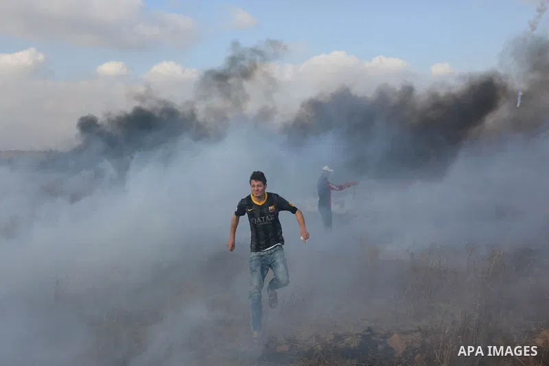 Palestinian protesters run for cover from tear gas canisters fired by Israeli security forces during clashes in a tent city protest where Palestinians demand the right to return to their homeland and against U.S. embassy...