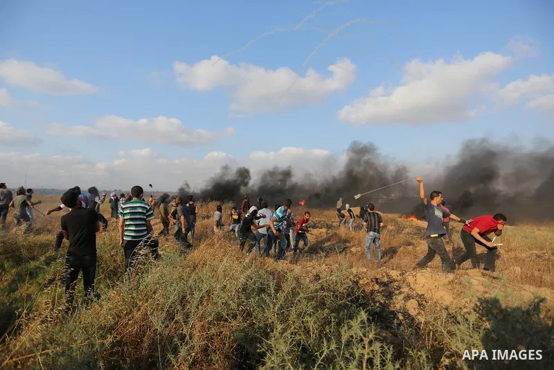 Palestinian protesters run for cover from tear gas canisters fired by Israeli security forces during clashes in a tent city protest where Palestinians demand the right to return to their homeland and against U.S. embassy...