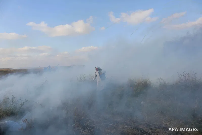 Palestinian protesters run for cover from tear gas canisters fired by Israeli security forces during clashes in a tent city protest where Palestinians demand the right to return to their homeland and against U.S. embassy...