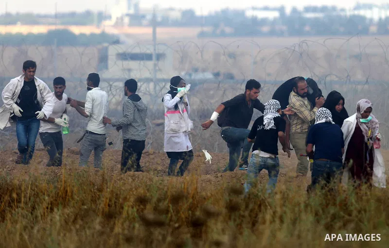 Members of Palestinian medical staff approach the barbed wire fence with Israel to tend to injured protesters during clashes at the Israel-Gaza border, in Khan Younis in the southern Gaza Strip, on June 1, 2018. Photo by...