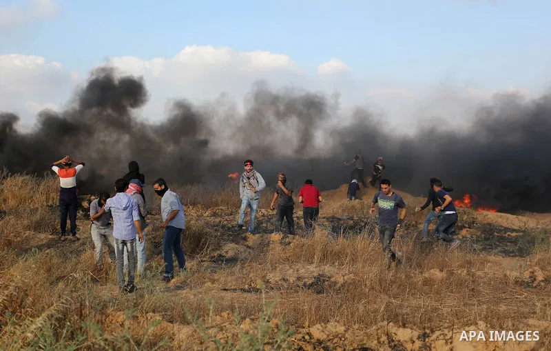 Palestinian protesters run for cover from tear gas canisters fired by Israeli security forces during clashes in a tent city protest where Palestinians demand the right to return to their homeland and against U.S. embassy...