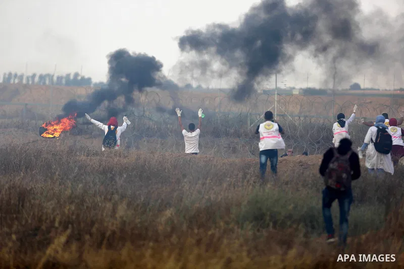 Members of Palestinian medical staff approach the barbed wire fence with Israel to tend to injured protesters during clashes at the Israel-Gaza border, in Khan Younis in the southern Gaza Strip, on June 1, 2018. Photo by...
