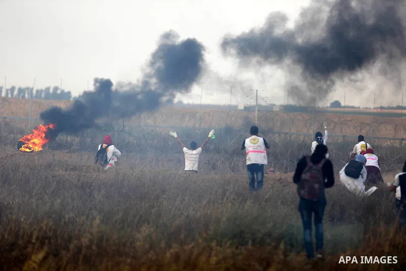 Members of Palestinian medical staff approach the barbed wire fence with Israel to tend to injured protesters during clashes at the Israel-Gaza border, in Khan Younis in the southern Gaza Strip, on June 1, 2018. Photo by...