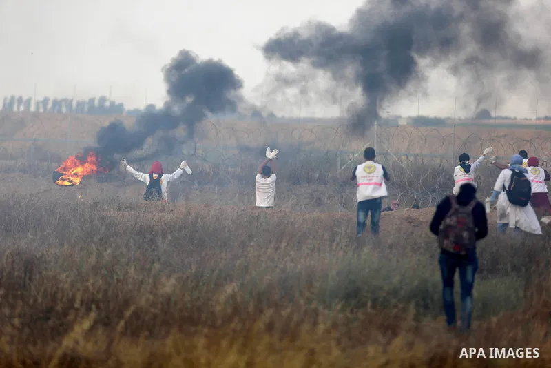 Members of Palestinian medical staff approach the barbed wire fence with Israel to tend to injured protesters during clashes at the Israel-Gaza border, in Khan Younis in the southern Gaza Strip, on June 1, 2018. Photo by...