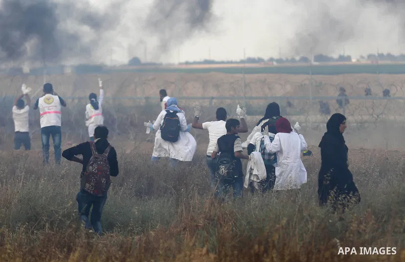 Members of Palestinian medical staff approach the barbed wire fence with Israel to tend to injured protesters during clashes at the Israel-Gaza border, in Khan Younis in the southern Gaza Strip, on June 1, 2018. Photo by...