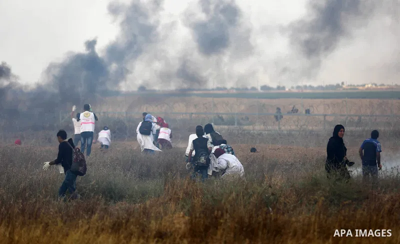 Members of Palestinian medical staff approach the barbed wire fence with Israel to tend to injured protesters during clashes at the Israel-Gaza border, in Khan Younis in the southern Gaza Strip, on June 1, 2018. Photo by...
