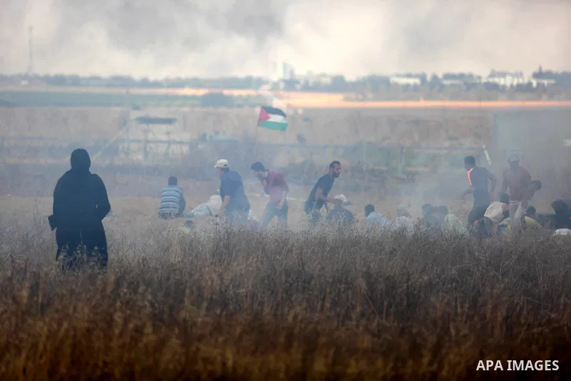 Members of Palestinian medical staff approach the barbed wire fence with Israel to tend to injured protesters during clashes at the Israel-Gaza border, in Khan Younis in the southern Gaza Strip, on June 1, 2018. Photo by...